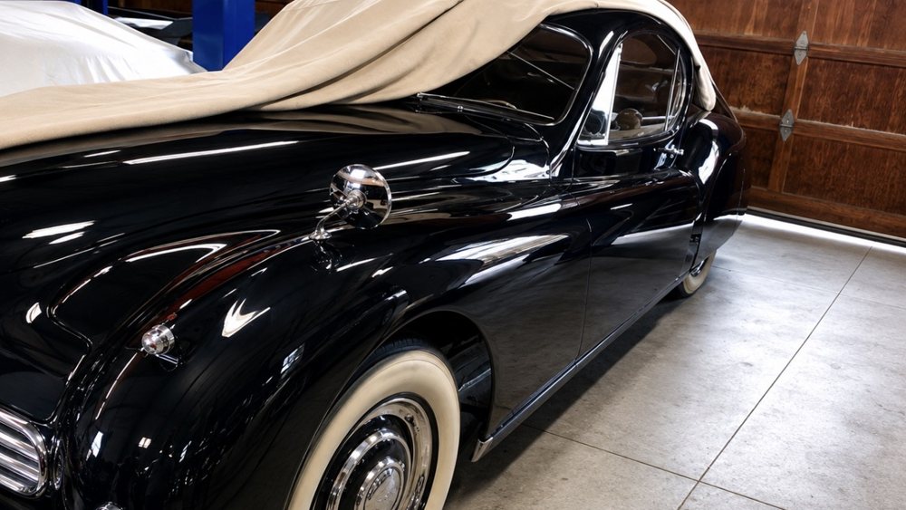 Classic black Jaguar coupe with a mirror-gloss finish and whitewall tires