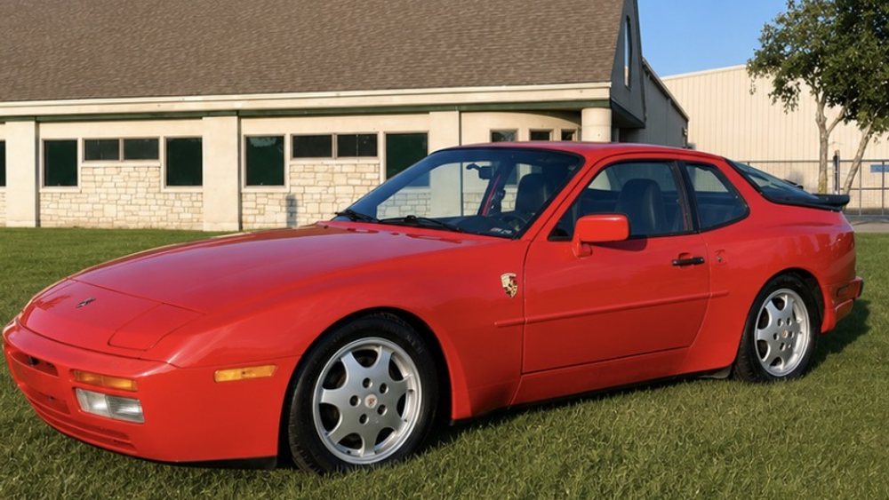 Detailed red Porsche 944 coupe, paint gleaming, parked on a cut lawn
